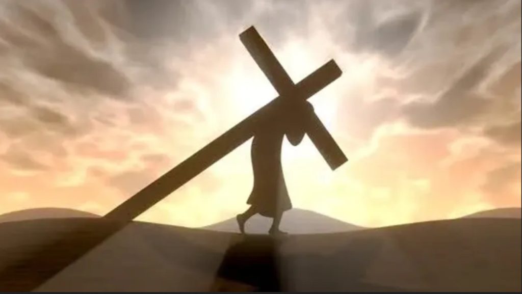 A silhouette of Jesus carrying a cross beneath a bright sky